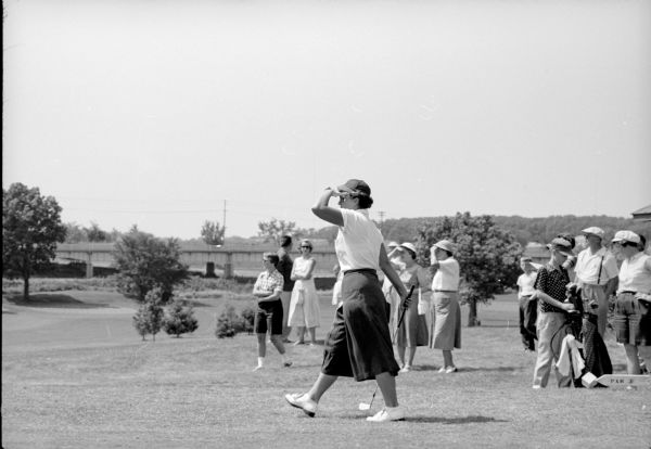 Joyce Ziske, 1952 women's golf champion, shading her eyes while strolling toward the green at the Blackhawk Country Club. She is competing in the 42nd annual state tournament of the Wisconsin Women's Golf Association.