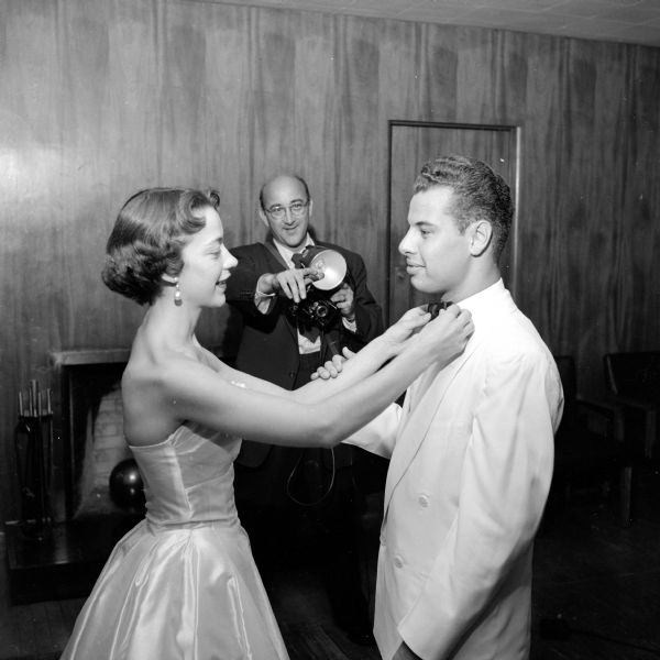 Preparing to have their picture taken at the university summer prom at the Memorial Union are Gloria Wruck and John R. Detter, both from Madison. Gloria is straightening John's bow tie. The photographer in the background is Bob Madigan.