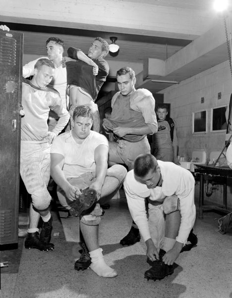 A group of Edgewood High School football players getting dressed for practice in the locker room. Standing left to right are: Dick Ellis, Doug O'Neill, Ron Schmelzer and Jerry Rudd. Mike Colby is sitting, and Pat Heffernan, kneeling. 
