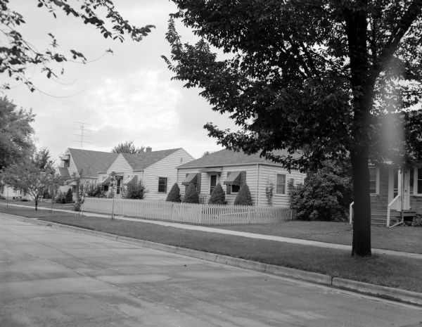 Houses along a Madison neighborhood street where carriers deliver the <i>Wisconsin State Journal</i>. One house on this paper route has a front yard enclosed by a white picket fence.