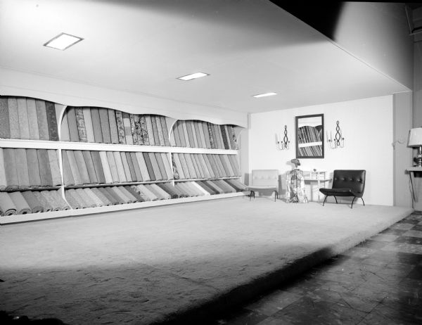 New enlarged display room for the floor covering and drapery shop at the Black Furniture Company, located at 315 West Gorham at State Street. Sample rolls fill the shelves along the wall.