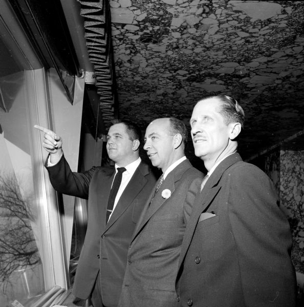 Representatives of business, labor and government at a pre-luncheon gathering to celebrate the opening of a new Sears Store. Looking out over Lake Mendota through the window of the Edgewater Hotel are guests (left to right): Arlie Mucks, Madison Chamber of Commerce; Wade Hampden, Sears District Manager, Chicago; and C.R. Brothers, manager of the new Sears Store.