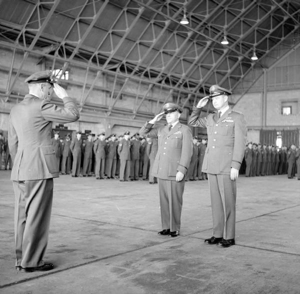 Chief Warrant Officer Sam Gubner (center) and Col. Frederick Nelander, Truax Field commander, return the salute of  Maj. John Pedigo (left), commander of the 432nd Fighter Interceptor Squadron, the unit to which Grubner was assigned when discharged. A native of Hungary, the 47-year-old Gubner became a naturalized American and joined the Army in 1924.