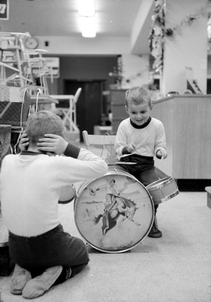 Jeff and Gregg Anderson playing on a drum set at the Wolff-Kubly-Hirsig store, Toyland. On the drum face is an image of a cowboy riding a bucking bronco.