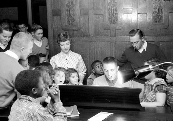 Fraternity member, Ted Stowe, playing piano as black and white children sing along at the Christmas party for the children of the South Side Community Center.
