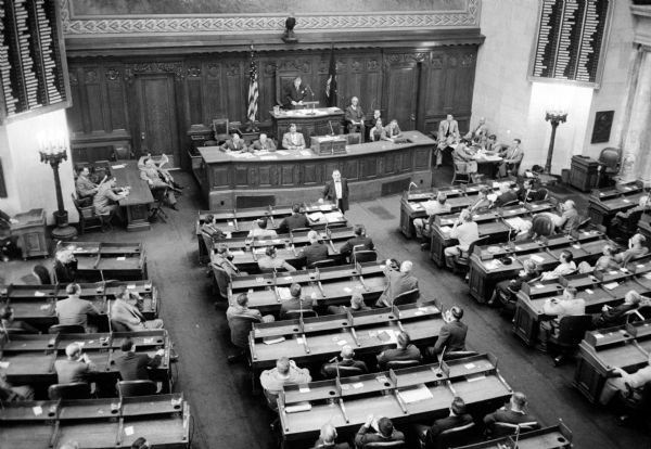 Elevated view of sworn in and seated members of the 1955 Wisconsin State Legislature Assembly listening to Assemblyman Robert Maratz (standing) nominate Mark Catlin, Jr. for Speaker.