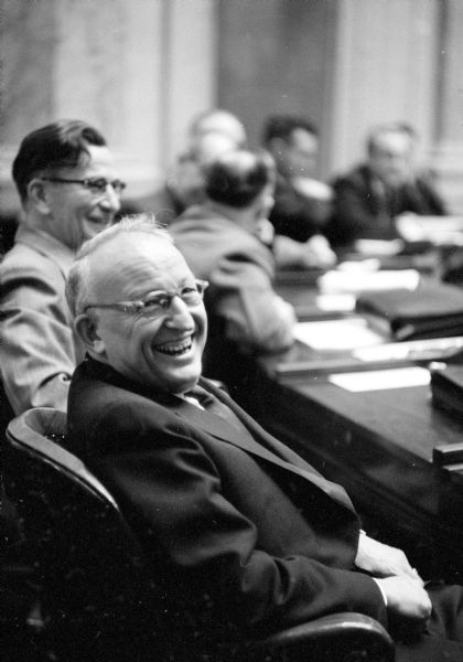 State Assemblymen Raymond Bice (R-LaCrosse) and William F. Trinke (R-Lake Geneva, in the foreground) sharing a laugh at the start of the 1955 State Assembly session.