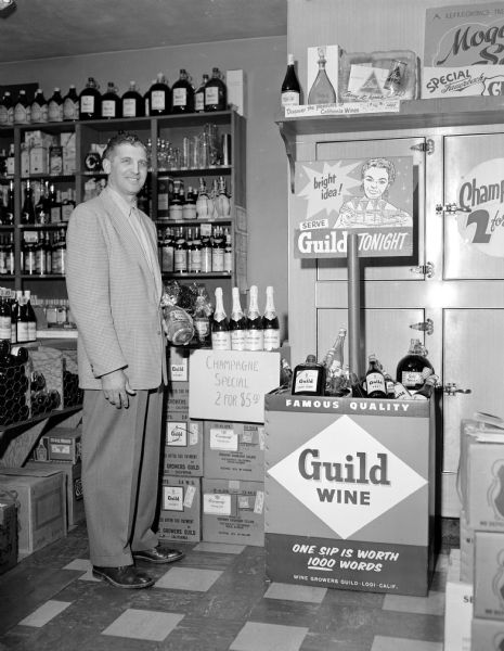 Paul Guten of Guild Wine Company standing next to a Guild Wine Company display in an unknown liquor store.