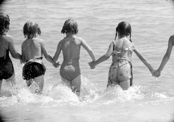 Three girls running into the water of Lake Wingra at the Vilas Park Beach.