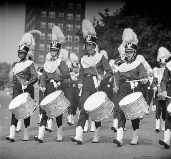 The drum line of a drum and bugle corps parading around Capitol Square. The musicians were participating in the third annual "Drums on Parade" invitational competition, sponsored by Zor Shrine, held at Breese Stevens field.
