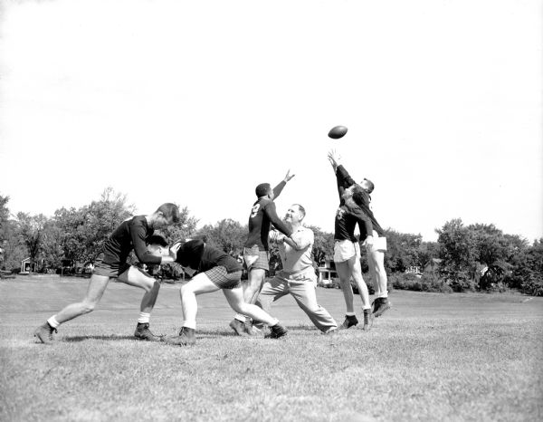 Edgewood High School football coach, Earl Wilke, demonstrates how to block on pass defense by interrupting Dick Miller's throw. Four other veteran players are shown taking part in the drill.