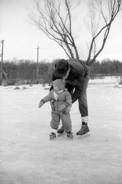 Francis Nerlinger is teaching his daughter, Susan Jane, to ice skate at the Vilas Park ice skating rink by Lake Wingra.