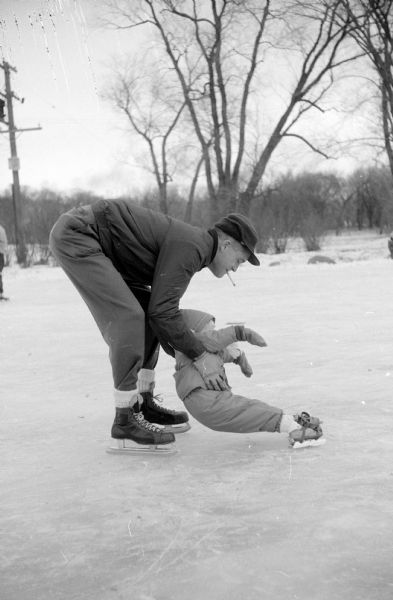 Francis Nerlinger helping daughter, Susan Jane, learn how to skate at Vilas Park ice rink by Lake Wingra.