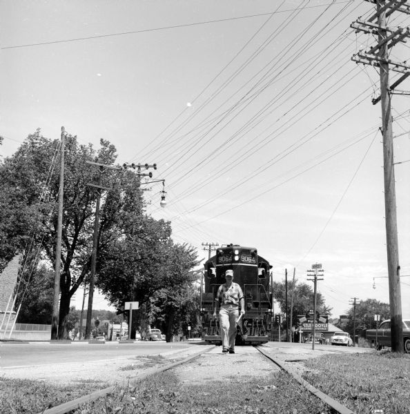 Illinois Central flagman R.D. DeRoche walking along the railroad tracks at the Monroe and Regent Streets crossing ahead of the engine after he activated warning lights.