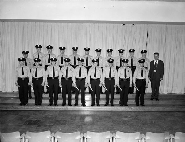 Sixteen new Madison policemen and three U.W. officers receiving their diplomas at a graduation ceremony held at the City of Madison Police Academy School. Graduates are shown with Lt. Herman Thomas, one of the instructors (2nd row-far right).
