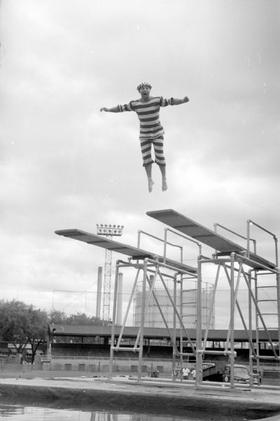 Water comedian, Eddie Rose, of the Sam Snyder's Water Follies performing his routine jumping off a high-level diving board during a show at Breese Stevens Field swimming pool. The show was sponsored by the Madison Police Protective Association.
