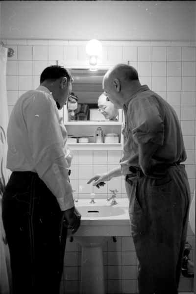 Bell captain of the Loraine Hotel, Tony Juisto, checking out a leaky faucet in a room's bathroom with the hotel engineer Charles Duggin.