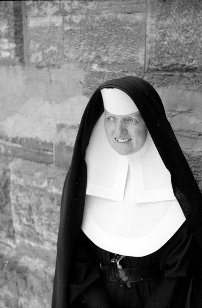 Attending a convocation session of the Wisconsin Congress of the Confraternity of Christian Doctrine at St. Raphael Cathedral is Sister Mary Dionetta of Religious Sisters of Mercy in Shullsburg, Wisconsin. She is wearing a wimple under a black veil, and has a crucifix tucked into her belt.