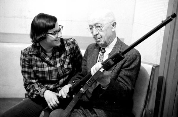Jan Bruhn, 15, chatting with her grandfather, A.T. Bruhn, at the Club. He headed a Junior Rifle Club in Denmark in 1884-1886 at the age of 9.
