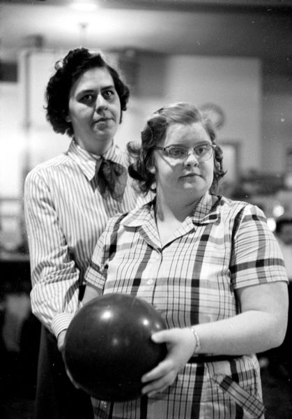 Ruby Graf and Della Killerlain posing with a bowling ball. They are two of about fifteen visually impaired participants who gather weekly on Tuesdays at Playdium Alleys located at 112 North Fairchild Street. None of the participants has vision better than 10 percent.