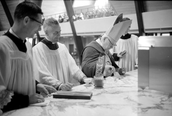During a ceremony to bless the altar in the newly built St. Bernard's Catholic Church on University Avenue in Middleton, Bishop William O'Conner seals a piece of marble into the main altar over a small copper box containing relics of saints.