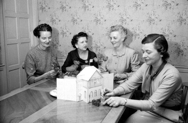 Members of the decorating committee for the annual Founders' Day Dinner for the Wisconsin Alumni Club looking at a model of Bascom Hall. From left are Sara Johnson, Anastasia  Castle, Margaret Russell, and Jean (?) Johnson. The banquet will be held at the Maple Bluff Country Club.
