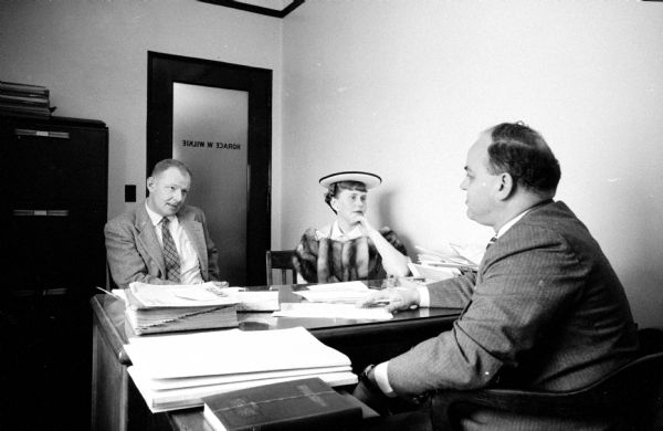 Staged visit to a divorce attorney in his office by a married couple. The husband is acted by Francis Fay, and posing as the wife, Miriam Leifer, vice-president of the Dane County Mental Health Association. The attorney's office belongs to Horace W. Walker.