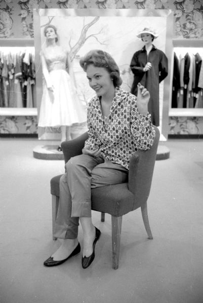 Teenage fashion show held at Harry S. Manchester women's clothing store to display twenty Vogue Pattern Service dress pattern styles. One of the models is Virginia Ward (4210 Mohawk Drive), a senior at West High School. She is modeling a two-piece lounging costume of trousers and an overblouse.