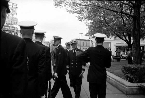 Vice-Admiral George L. Russell, deputy chief of Navy operations, was honored Wednesday in his first visit to Madison. He is shown here inspecting an honor guard on Capitol Square. Pictured here are Midshipman David A. Link, and, in the background, Rear Admiral H.H. Caldwell, Chief of Naval Air Reserve training center (of Glenview, Illinois).
