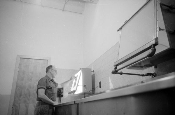 George H. Beyler, engraving photographer, inspecting a negative on a viewer for the new ultra-modern photoengraving plant at Madison Newspapers.