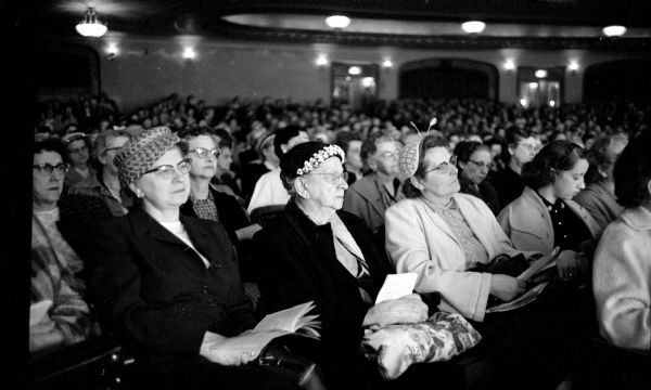 Three attendees in the foreground watch a demonstration on meat cooking at the three-day "Rhapsody of Recipes" Cooking School at the Orpheum Theater. Wearing hats they are (left to right): Mrs. Merwin Roberts, Helen Gundlach, and Ann Bussey. Other people are not identified.