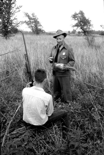Conservation Warden Albert Koppenhaver gives a talking-to to a youthful game law violator for shooting a pheasant out of season. 