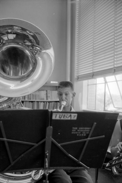 Tuba player Fred Mikrut from Ogdensburg appears to be acquiring air to blow his big horn from a pipe in the background, which seemingly sticks out of his head. Actually he is practicing at the Summer Music Clinic at the University of Wisconsin.