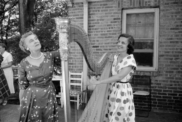 Mary Collins (right) explains some of the intricacies of a harp to hostess Eleanore Conlin. She played a program of harp selections for the annual missionary tea sponsored by the Women's Society of Christ Presbyterian Church.
