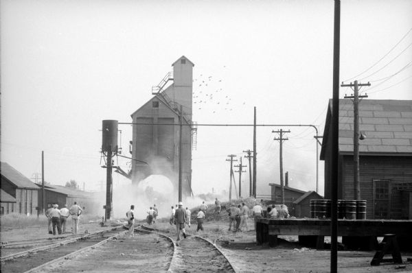 North Western Railroad employees attempt to demolish a concrete coal chute at the railroad's East Side yard at Commercial and Sherman Avenues. Groups of men look on to what proves to be unsuccessful.