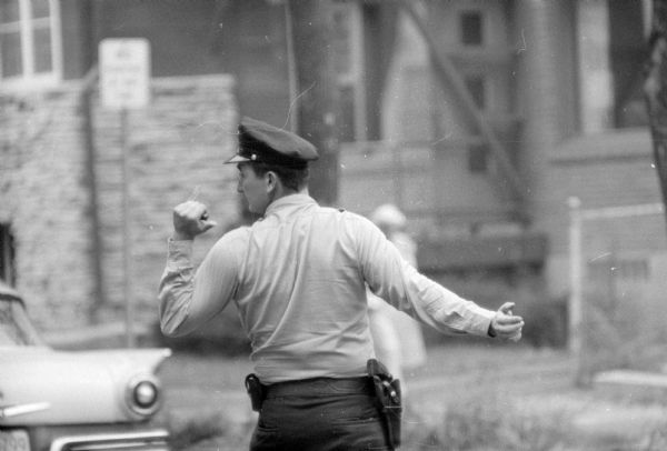Backside of Madison Police Patrolman Joseph Jones (1148 Jenifer Street), who is directing traffic at the busy West Dayton Street and Randall Avenue intersection. His gun is visible on his belt.