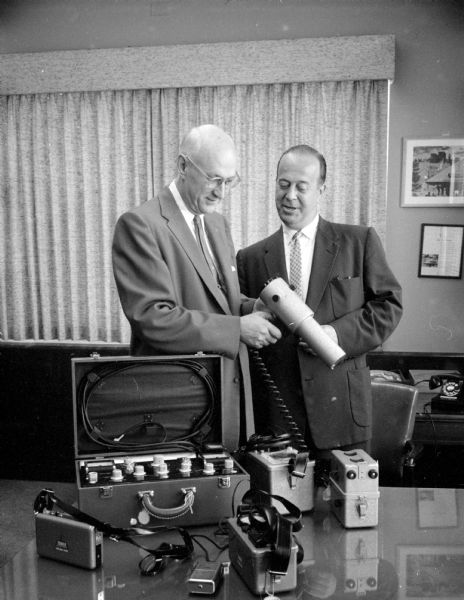 Richard C. Emmons (left), Professor of Geology at U.W., being presented thirteen Geiger counters and scintillation counters by E.L. Diener, manager of the Madison branch of Sears, Robuck and Company. The nation-wide company is giving counters to universities and schools throughout the country.