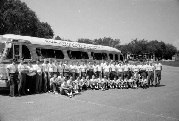 Members of the Boy Scout Corps posing for a group portrait prior to leaving on a trip to Florida to compete in the VFW national competition. The Scouts are shown in front of their Badger Coaches bus.