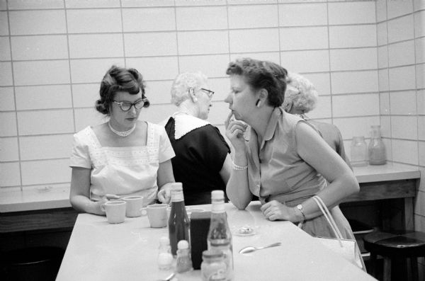 Employees of the new City-County Building enjoying refreshments in the canteen. Marion Burns (left) and Dorothy Gaukel visit at a standup coffee counter before ceramic mugs. Two other women are behind them.