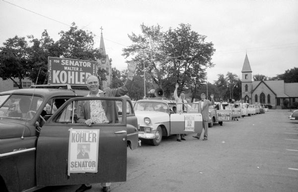 A thirteen-car caravan tours Dane County campaigning for former Governor Walter J. Kohler, the Republican nominee for United States Senator. The caravan is shown at the start of the tour in the city parking lot on the 200 block of East Washington Avenue.