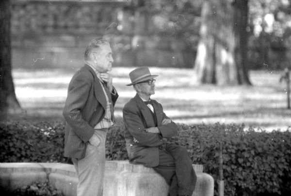 Two men watching the demolition of the Pioneer block and Madison Theater from the Capitol grounds in Madison. The photograph was taken with a new telephoto lens.