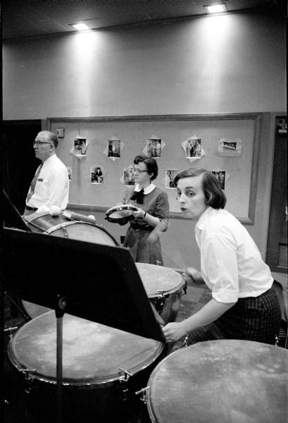 Members of the percussion section of the Madison Civic Symphony orchestra at rehearsal in Scanlan Hall. Helen Dahm (right) is playing the tympani, Marian Kanable is on tambourine, with Elmer Ziegler in the background.