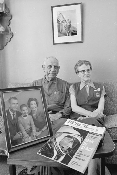Portrait of Charles & Victoria Slayton, parents of astronaut Donald "Deke" Slayton, sitting in their home in Leon, Wisconsin with framed photographs of their son Donald - on a table as a boy with them and on the wall as a pilot. A special issue of <i>Space World</i> magazine with Donald's picture on the cover is the table. The article title reads "Man in Space: The Flight of the First Astronaut."