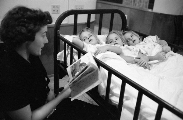The three daughters of Mr. and Mrs. William Wills, 805 Pulley Drive, have their tonsils removed on the same day at St. Mary's Hospital. Mrs. Wills is reading to her triplets (left to right) Susan, Jacqueline, and Catherine. 