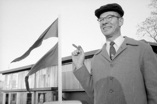 Stanley Bokelmann, 337 Orchard Drive, a local builder, celebrates the birth of twin sons at St. Mary's Hospital by hosting two blue pennants on the flag pole in front of his home. The twins are named John Stanley and William Thomas after their grandfathers. He is also smoking a cigar.