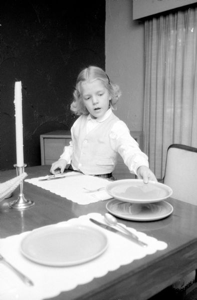 Martha Jean Johnson, 6, daughter of Dr. and Mrs. Everett F. Johnson is shown helping earn her weekly allowance by setting the table and doing other simple household tasks. Her father gives her an extra nickel for each chore and she then gives it to the Empty Stocking Club.