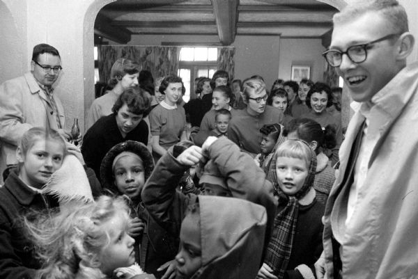 Here members of Phi Delta Theta and Gamma Phi Beta welcomed a group of happy youngsters at Neighborhood House located at 29 South Mills Street. The party included games, prizes, singing, and all that the children could eat. A crowd of children are seen among fraternity and sorority members.