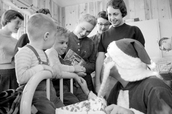 Kappa Delta sorority members look on while some children are talking to Santa Claus. The children are "shut-ins" at Morningside sanatorium. Morningside sanatorium was at 300 Femrite Drive and was a residential tuberculosis treatment center. Sigma Nu fraternity also sponsored the event.