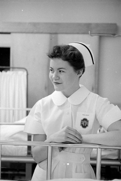 Student nurse, Mary Jo Oxem, at the bedside of a patient. As one of the 125 students of St. Mary's School of Nursing, she is posing for a series of photographs taken during a typical day of a senior student nurse.