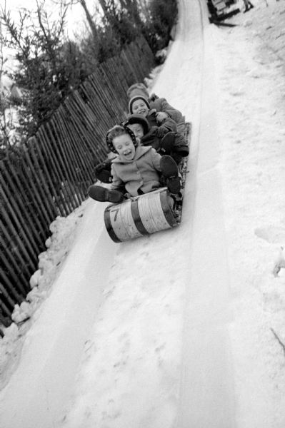 Children going downhill on a toboggan at Olbrich Park don't seem to mind if scarves are flying as they squeal, scream and shout. The toboggan is made of wood and the hill is a steep man-made slide of ice.